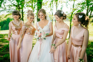 Bride with beautiful bridesmaids in pink dresses holding bouquet. Best friends at wedding day photoshoot. 