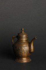 ancient oriental metal teapot on dark background. antique bronze tableware