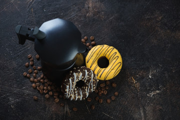 Moka coffee pot, coffee beans and donuts over dark brown stone background, high angle view with...