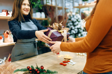 Female seller gives to customer christmas gift box