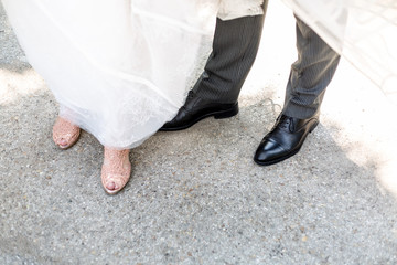 the shoes of a groom and a bride standing together