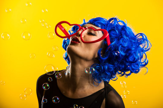 Cute girl wearing vibrant blue wig playing and blowing bubbles