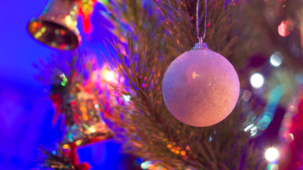 White glitter ball on the branch of the Christmas tree