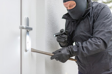 Einbrecher will mit einer Brechstange eine Haustür aufhebeln