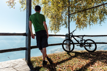 Mountainbiker blickt vom Berg Cimetta über Locarno, Ascona und den Lago Maggiore, Tessin, Schweiz.