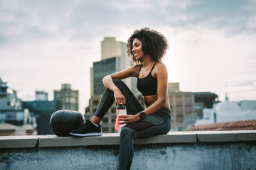 Fitness woman sitting on rooftop taking break from workout