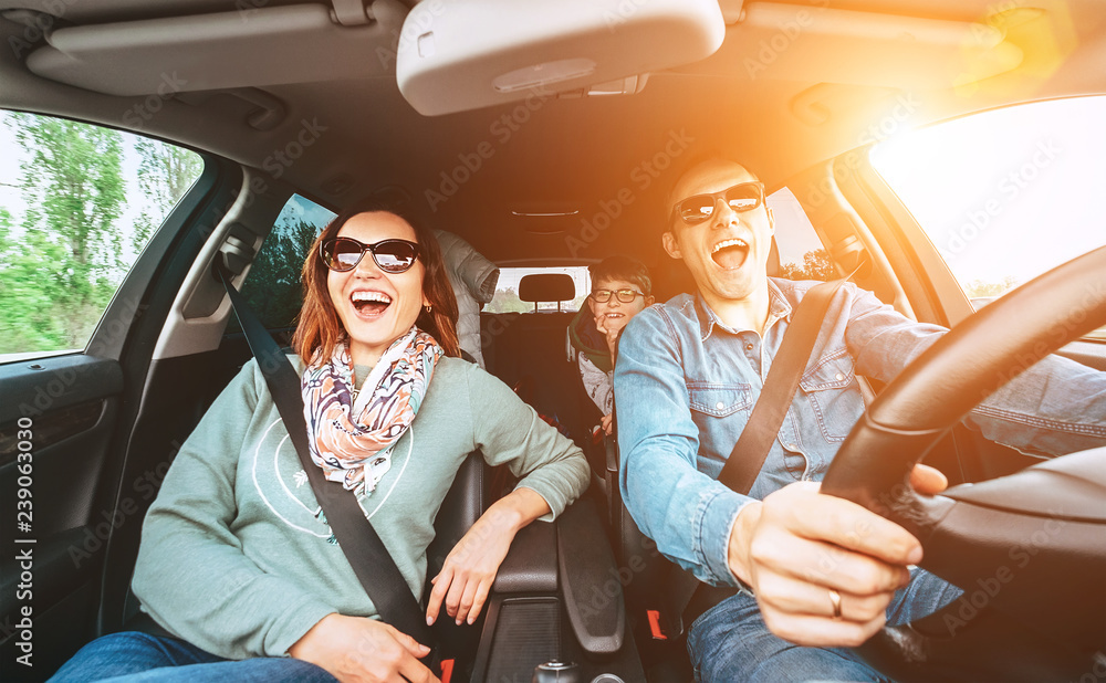 Wall mural Cheerful young traditional family has a long auto journey and singing aloud the favorite song together.  Safety riding car concept wide angle view image.