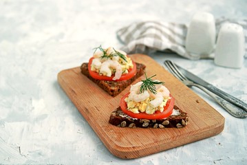 Rye open sandwich with tomato, egg salad and shrimps. Danish cuisine.