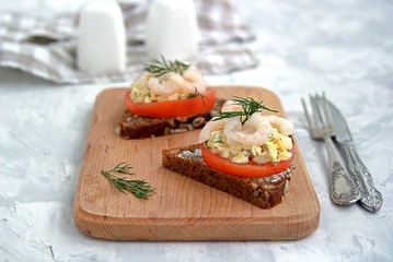 Fototapeta na wymiar Rye open sandwich with tomato, egg salad and shrimps. Danish cuisine.