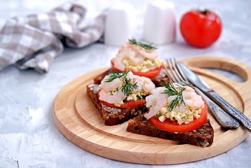 Rye open sandwich with tomato, egg salad and shrimps. Danish cuisine.