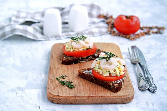 Rye open sandwich with tomato, egg salad and shrimps. Danish cuisine.