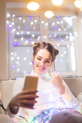Young woman taking a selfie with christmas lights