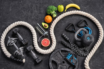 Sports equipment and organic food on a black background. Top view. Motivation