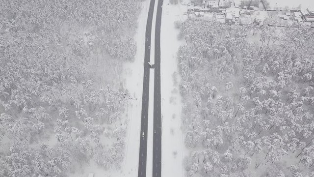 Aerial - Top down tracking shot of blue car drifting on snowy road in forest