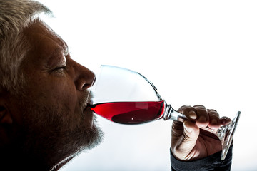 a man drinks red wine from a glass