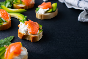 Snacks, bruschetta with cream cheese, avocado and salmon