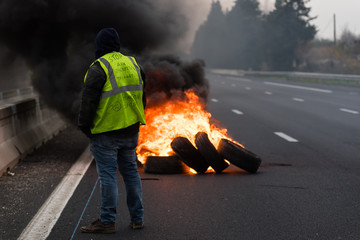 Gilet jaune de dos devant un feu de pneus sur l'autoroute - Manifestation France