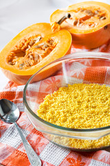 Raw washed millet in a glass pan in the process of cooking milk pumpkin porridge with raisins