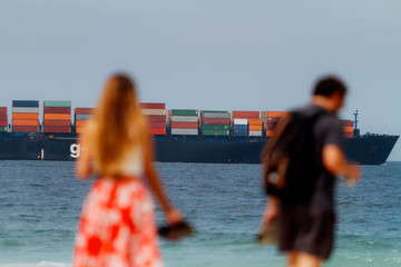 Cargo ship passes in front of Copacabana beach while a couple out of focus is accommodated