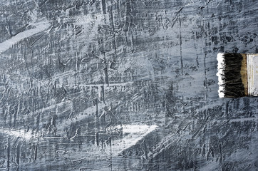 portion of the brush in black and white paint on the background of a concrete painted gray background on the left