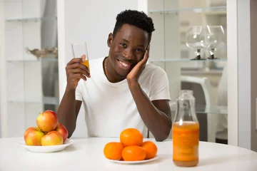Papier Peint photo Jus African american man drinking juice in kitchen