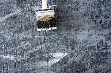 part of the brush in black and white paint on the background of a concrete painted gray background from above