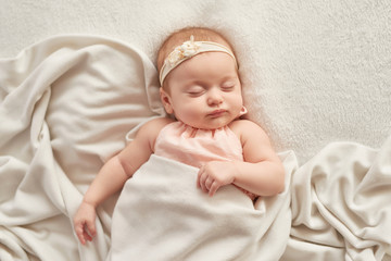 Newborn baby girl, three months old, lies in white blanket with heart. Baby goods packaging template. Closeup portrait of newborn baby with smile on face. Healthy and medical concept. Valentine card