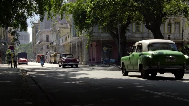  iconic old 1950's vintage classic american cars driving on famous alley street in old neighborhood Havana, Cuba