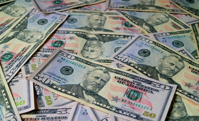 Fototapeta na wymiar Heap of United States fifty dollar bills with selective focus and blurred background 