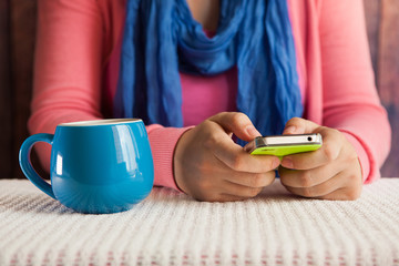 Woman typing text on phone and drinking tea, communication concept