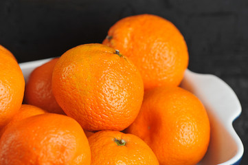 Tangerines on the dish. Close-up. Dark background. Macro shooting.
