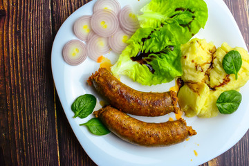 Sausages with green salad, balsamic vinegar, mashed potatoes, red onions, on a wooden rustic table. blur, clean, bright, authentic, retro, contrast, top view. Copy space.