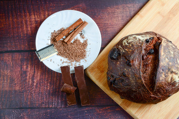 Chocolate bread, cinnamon and chocolate sticks on the wooden rustic table. Clean, bright, authentic, retro, contrast, top view. Copy space.