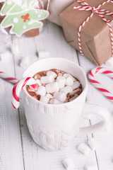 Obraz na płótnie Canvas Cup of cocoa or chocolate on wooden Christmas background. Winter hot chocolate drink with marshmallows, snowman and a fir-tree cookies, candy canes