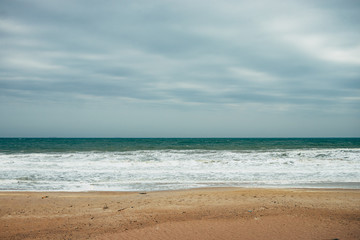 Fototapeta na wymiar Ocean waves with foam lapping on the sandy beach
