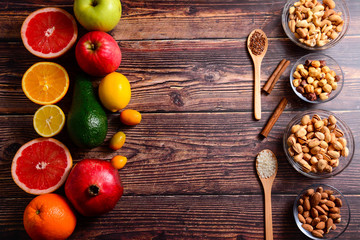 Fototapeta na wymiar Copy space. Healthy food concept - citrus, avocado, apple, nuts, pomegranate, sliced. Wooden rustic table.