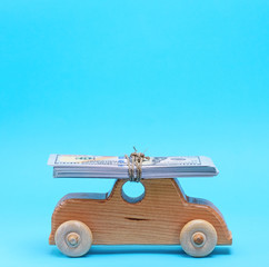  wooden children's car carries on the top of the roof a stack of paper banknotes