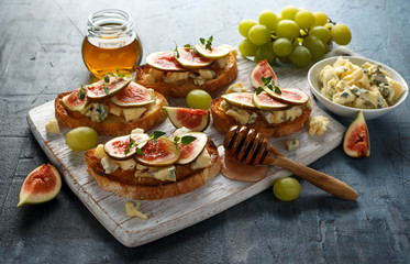 This Fig and Gorgonzola tartines, toast, bruschetta. drizzled with honey on white wooden board