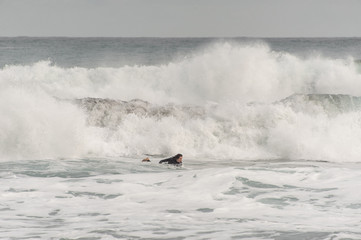 Brunette guy in the black swimsuit floating on a surf on the sea