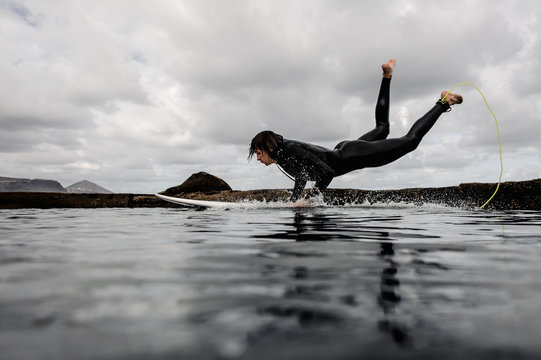 Brunette Guy In The Black Swimsuit Jumping On A Surf On The Sea