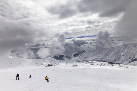 Skiers on snowy ski slope and cloudy storm sky before blizzard