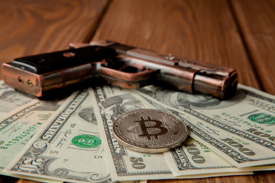 Black pistol, dollars and coin in the form of bitcoin on wooden background