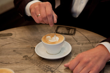 Fototapeta na wymiar bride and groom hold cups with cappuccino and look at each other