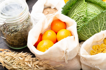 Zero waste grocery shopping. Package-free food on dark wooden table with texture. Fresh vegetables and fruits in Eco cotton bags. Plastic-free package