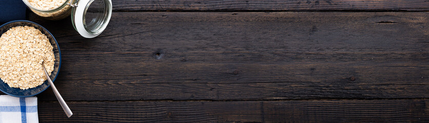 Rolled oats, healthy breakfast cereal oat flakes in bowl on dark wooden table with texture, copy space