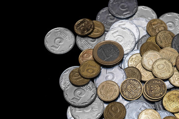Ukrainian coins with one euro coin isolated on black background. Close-up view. Coins are located at the right side of frame. A conceptual image.