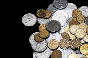 Ukrainian coins with one euro coin isolated on black background. Euro coin is uncolored. Close-up view. Coins are located at the right side of frame. A conceptual image.