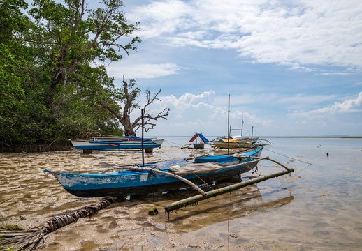 Seashore at Bohol island with low tide and old fisherman boats front view. Philippines.