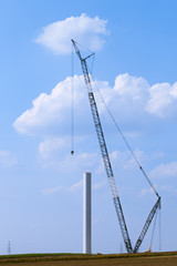 Blue crane tower constructing windmill with background of blue sky. Wind Turbine Construction