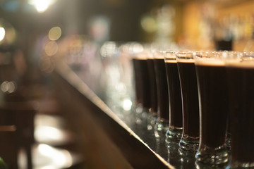 Beer glasses with dark beer are on the bar counter